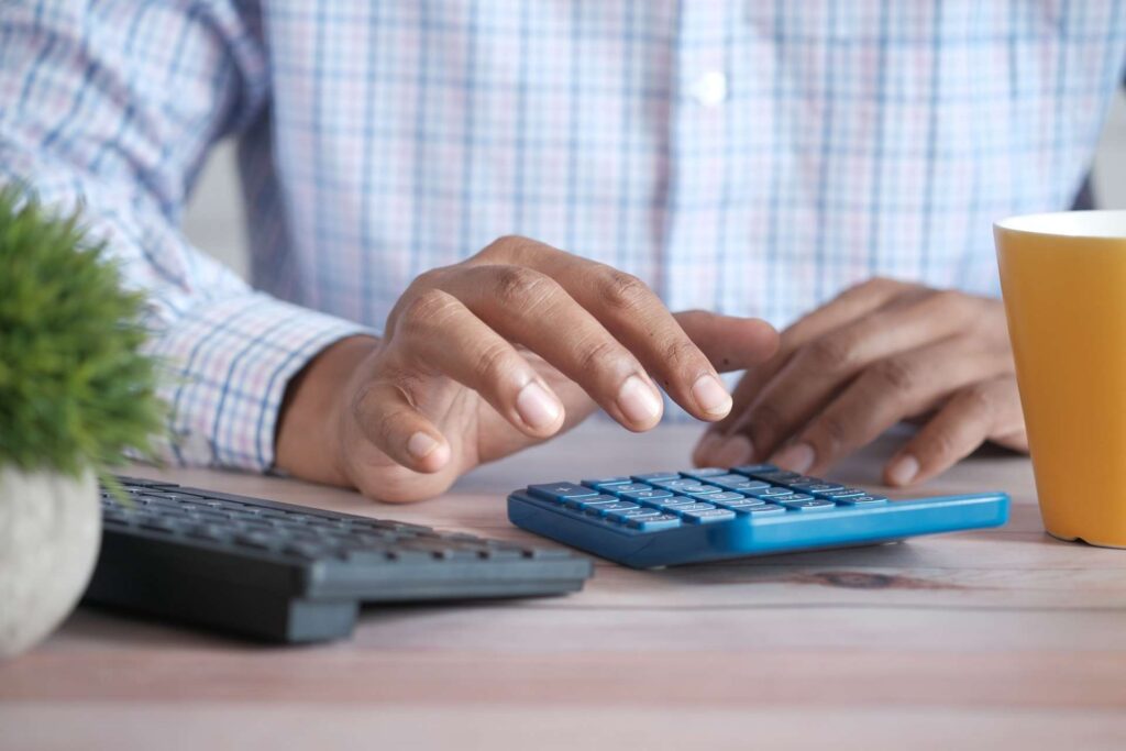 Person typing budget plan spreadsheet on calculator
