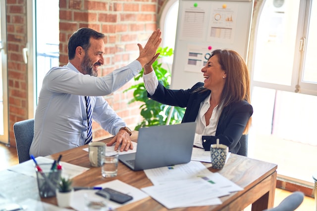 Two people high-fiving as a sign of good work for Human Talent Management