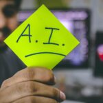 Hombre sostiene un post it con el acrónimo de inteligencia artificial para capacitaciones