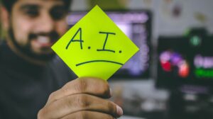 Hombre sostiene un post it con el acrónimo de inteligencia artificial para capacitaciones