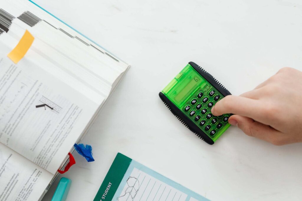 persona con documentos y con una calculadora verde digitando números para hacer un balance general